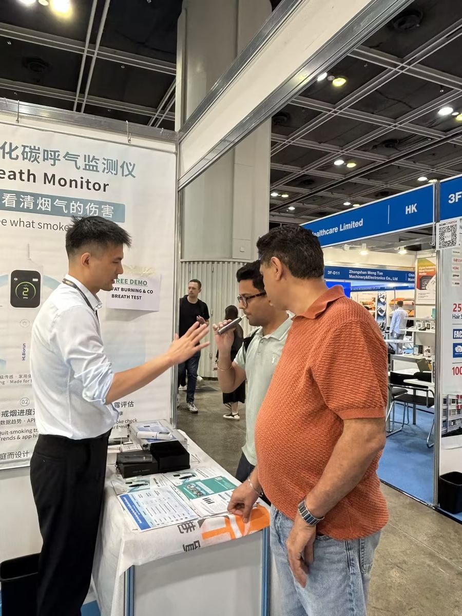 汇立生物工作人员在香港电子展展位向国际买家演示呼气检测产品，买家现场体验一氧化碳呼气监测仪